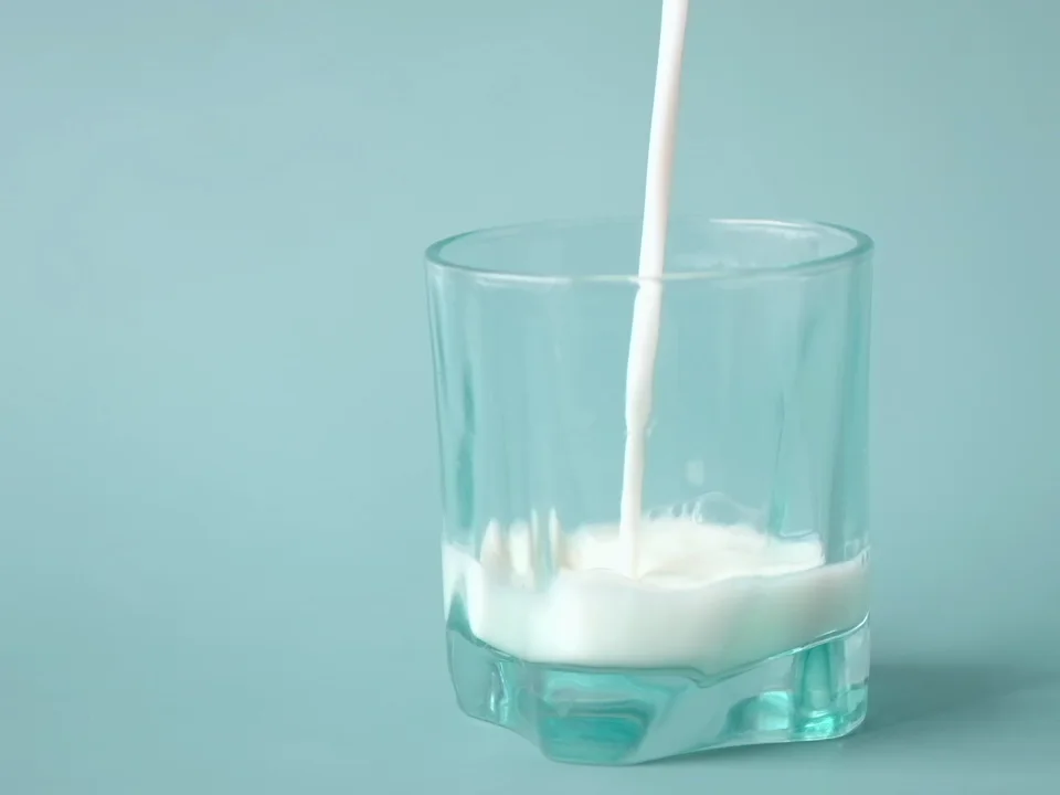Real milk stream being measured into a clear glass