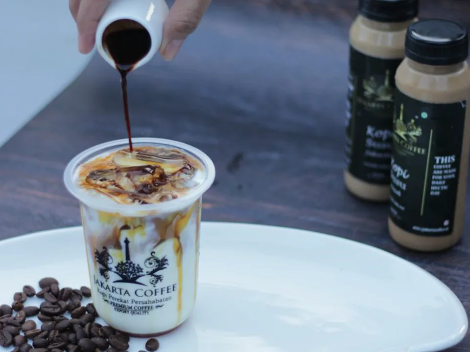 Syrup being poured into a prepared coffee drink